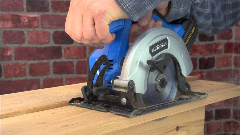 Craftsman wielding a battery-powered circular saw through thick oak plank in sunlit garage.